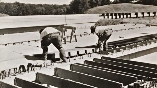 Workers laying a plywood base over joists